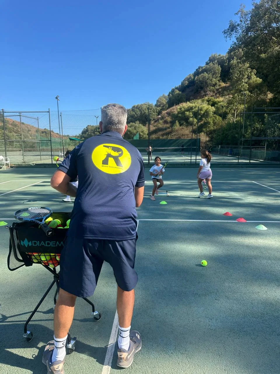Rhino coach leading a junior tennis session in the sunshine
